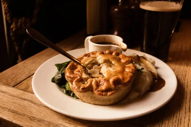 Traditional savory chicken pot pie served in pub with beer in the background