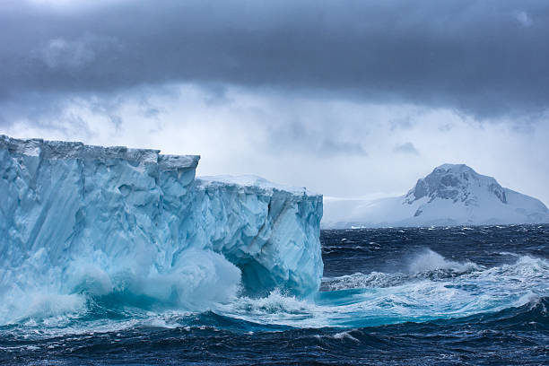 enorme iceberg che galleggia in antartide in una tempesta - uncultivated snow ice antarctica foto e immagini stock