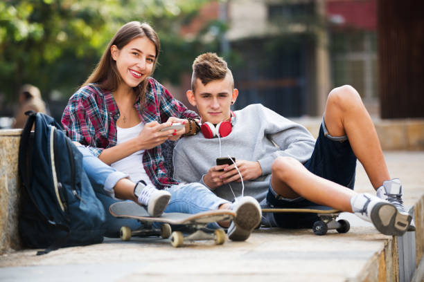 adolescente y su novia con los smartphones - video game child handheld video game little boys fotografías e imágenes de stock