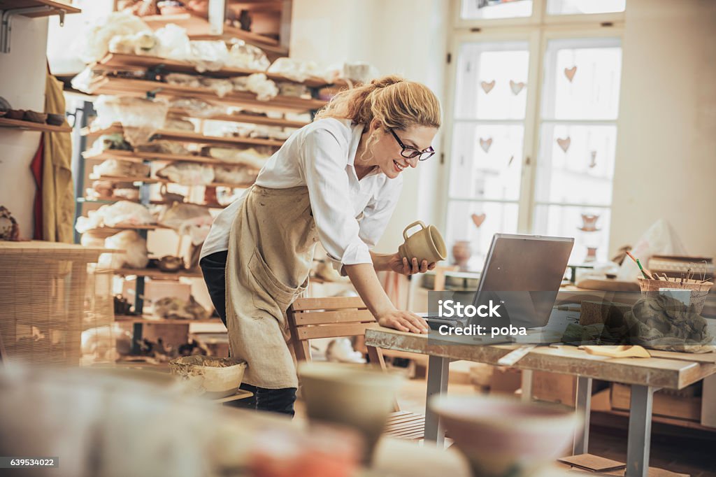 Potter entrepreneur using laptop  in workshop Small Business Stock Photo