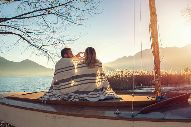 Young couple by the lake making heart shape finger frame