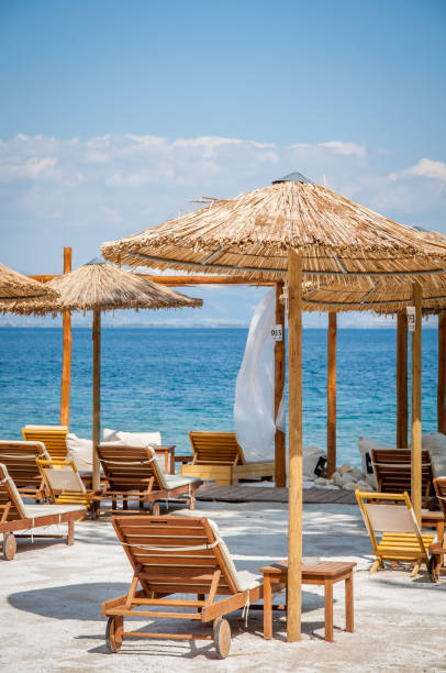 beach with wooden umbrellas and sunbeds - beach palm tree island deck chair imagens e fotografias de stock