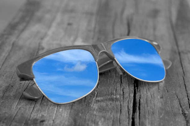 istock Sunglasses reflecting blue sky on texture wooden plank. 639548898