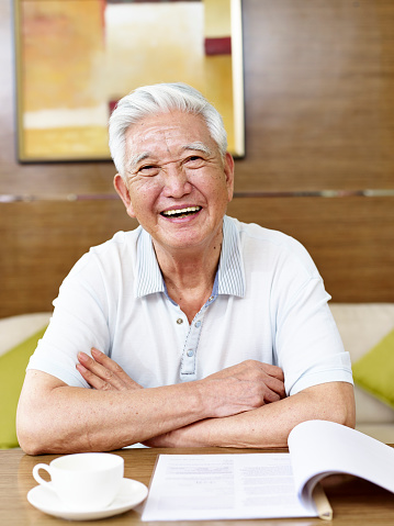 senior asian man reading a book or document in study room