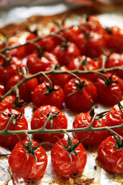 Baked cherry tomatoes Baked cherry tomatoes on a sheet of baking paper confit stock pictures, royalty-free photos & images