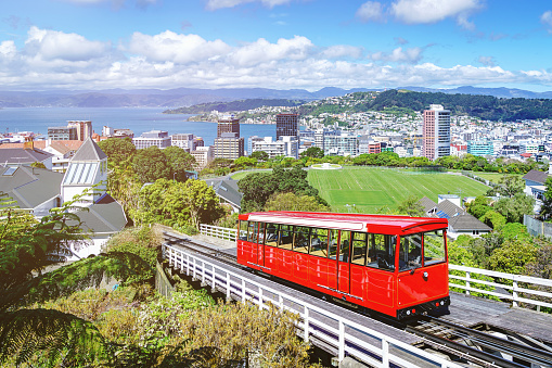Wellington Cable Car Red Trolley with Downtown Wellington Cityscape in Summer under beautiful blue summer sky. Wellington, North Island, New Zealand, Oceania.