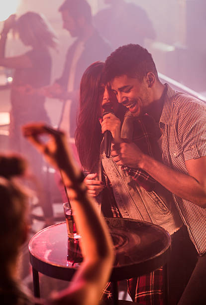 Happy couple singing karaoke and having fun in the disco.