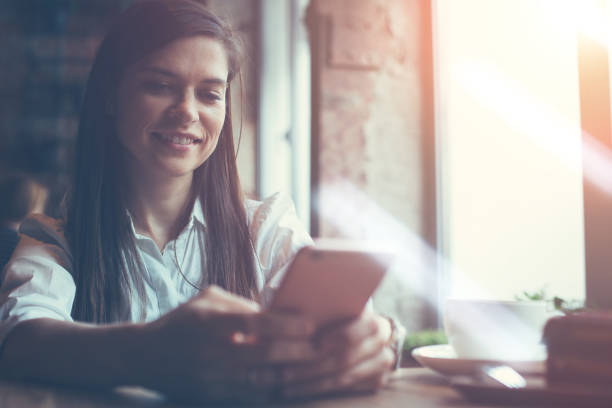 istock Smiling woman using mobile phone sitting alone in cafe 639568432