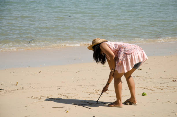 istock Asian thai woman posing and writing on the sand beach 639569846