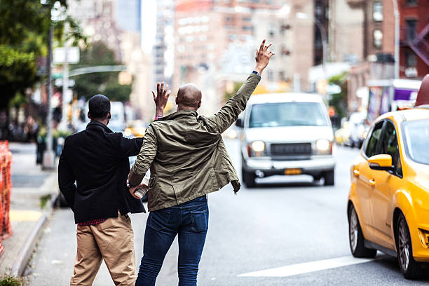 männer paar winkt einem taxi in new york - people traveling business travel travel new york city stock-fotos und bilder