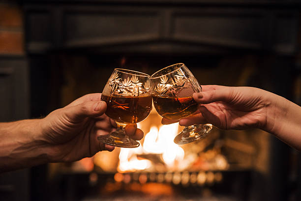 Couple with Two glasses of alcoholic drink  in front fireplace Couple with Two glasses of alcoholic drink  in front warm fireplace brandy photos stock pictures, royalty-free photos & images