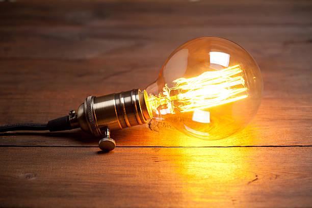 istock Vintage incandescent Edison type bulb on old wooden table 639576982