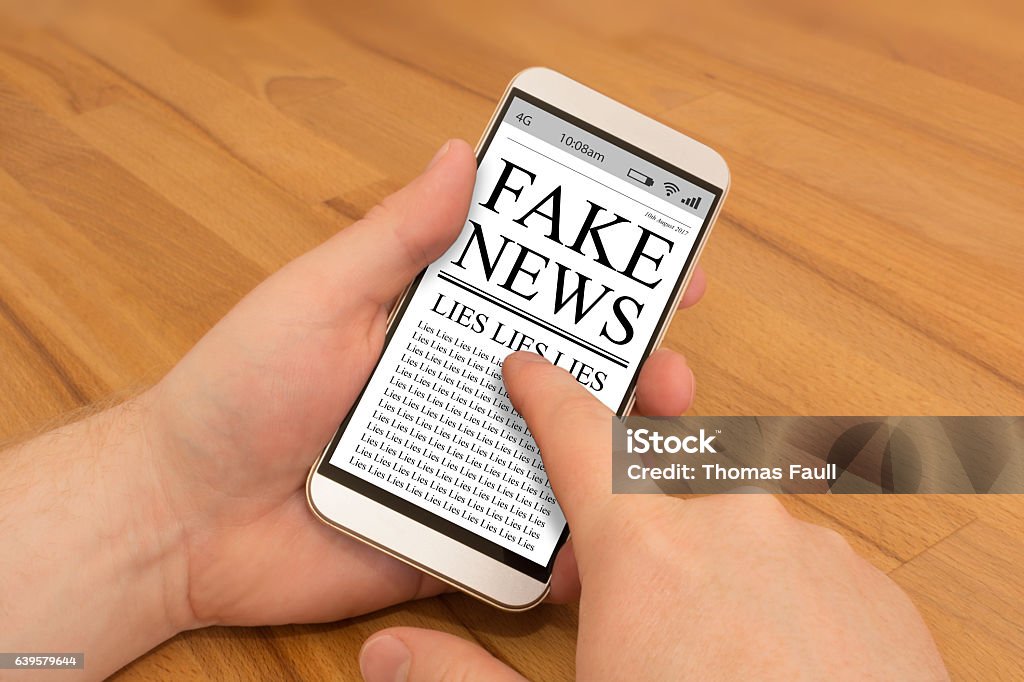 Leggere fake news su smartphone - Foto stock royalty-free di Fake news