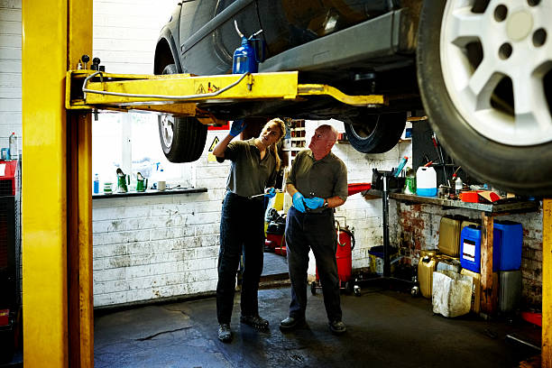 istock Mechanics working under car on lift in auto shop 639580696