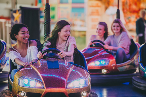 A group of girls, two teams in dodgems trying to bump others, laughing and having fun!