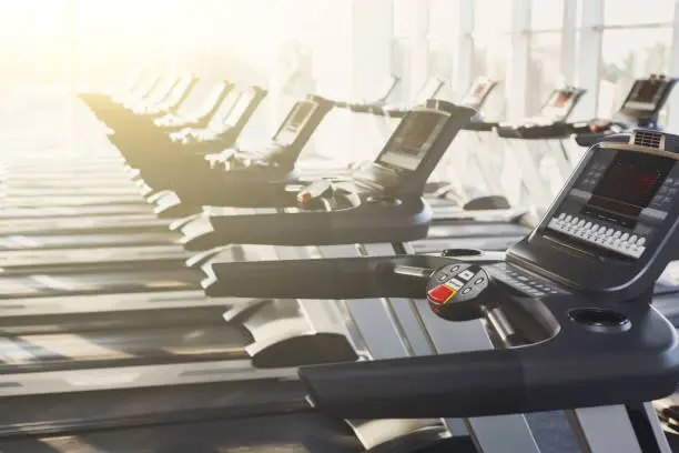 Photo of Modern gym interior equipment, treadmill control panels for cardio training