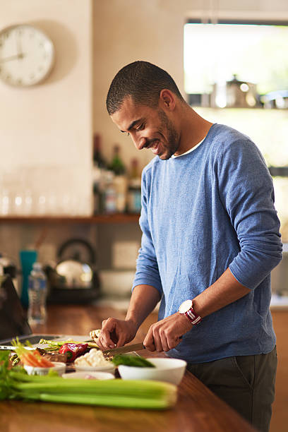 Making a healthy meal from scratch Shot of a happy young man preparing a healthy snack at home bachelor stock pictures, royalty-free photos & images