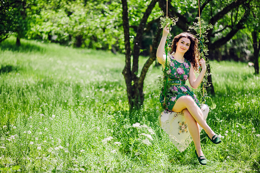 woman ride on a swing. Green park.