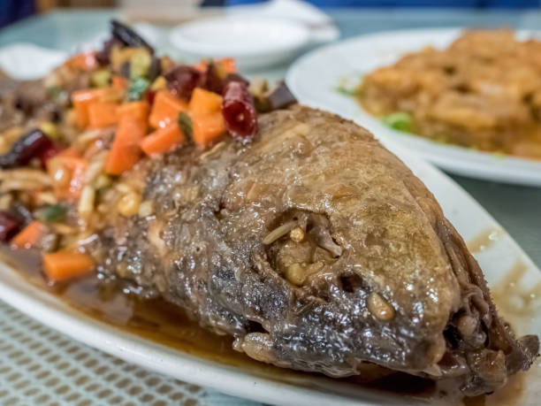 Braised Yellow Croaker fish or Corvina - Beijing-style. The fish is fried and then braised with a spicy sauce containing diced carrots and chopped dried chilli.