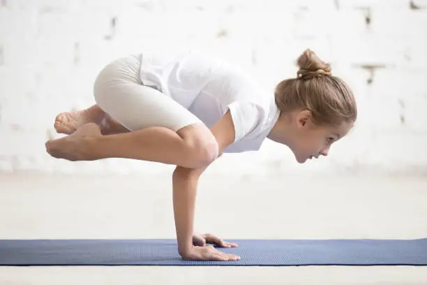 Photo of Girl child in Bakasana pose, white studio background