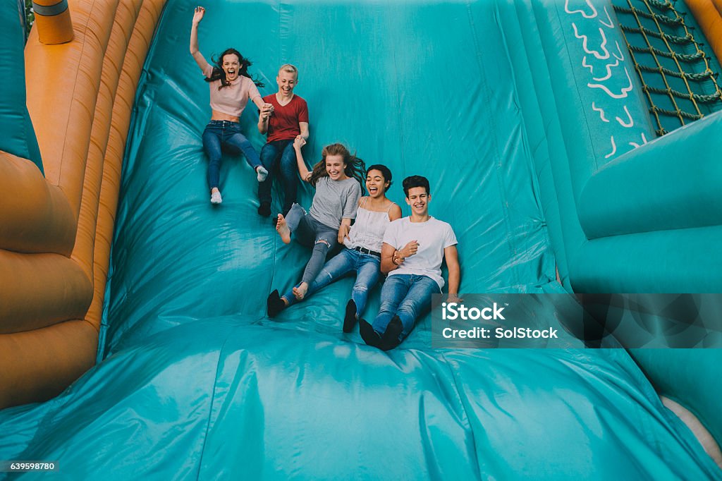 Teens Jumping Down Slide A group of young teens jumping down the slide at an amusement park! Bouncy Castle Stock Photo