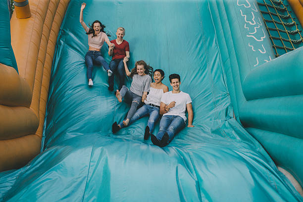 Teens Jumping Down Slide A group of young teens jumping down the slide at an amusement park! Bounce House stock pictures, royalty-free photos & images