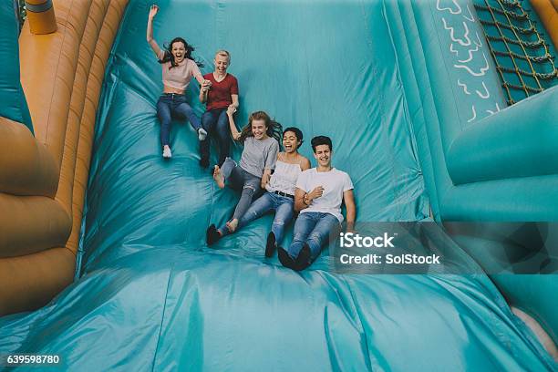 Teens Jumping Down Slide Stock Photo - Download Image Now - Bouncy Castle, Teenager, Amusement Park
