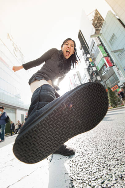 Rebel Asian Woman in Backlight Asian Woman kicking in Backlight. Photo taken at Tokyo iStockalypse japan women human foot japanese culture stock pictures, royalty-free photos & images