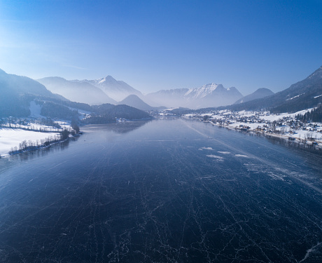 Arial Panorama of the frozen Lake Grundlsee, Austrian Alps Winter Panorama, Nature Reserve. Huge Stitched Alps Panorama. Great Detail. You can see the Mountains Zinken and Sarstein and all the way to the famous Glacier Dachstein. People Ice Skating. Converted from RAW.