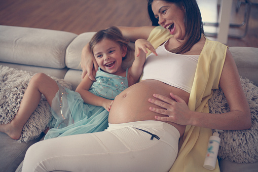 Pregnant woman having fun with her daughter at home.
