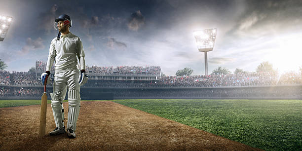 Cricket player batsman on the stadium Cricket player standing on a cricket field. The batsman is wearing unbranded sports cloth and equipment. The bleachers full of people are blurred behind the player. There is intentional lenseflares on the image. batsman photos stock pictures, royalty-free photos & images