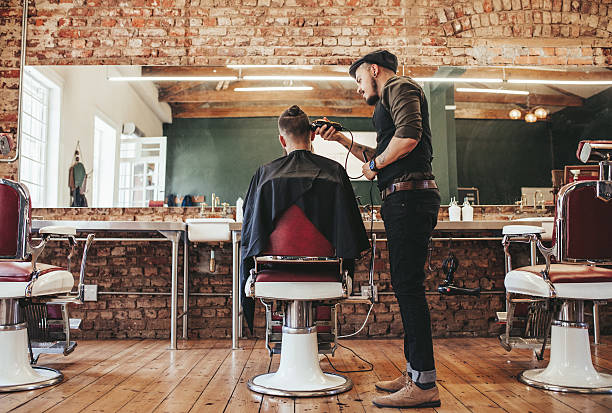 Hairstylist serving client at barber shop Rear view shot of handsome hairdresser cutting hair of male client. Hairstylist serving client at barber shop. barber shop stock pictures, royalty-free photos & images