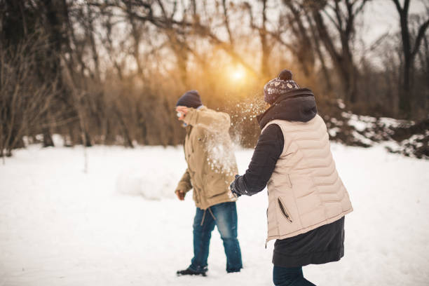 Photo of young family having a snowball fight on a snowy winter day outdoors