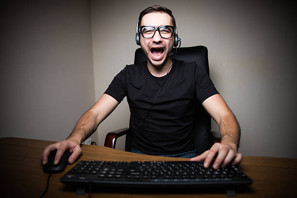 istock Scream man with headphones playing computer games in dark room 639609944