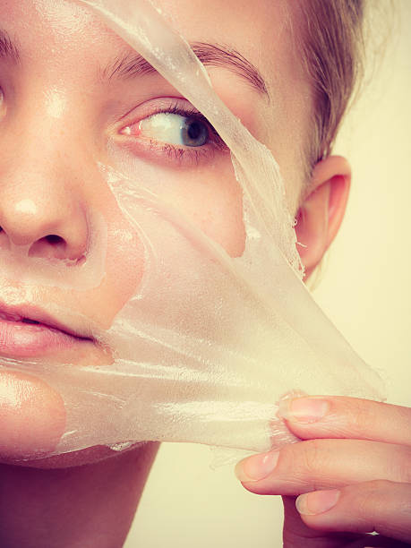woman removing facial peel off mask closeup - peel off imagens e fotografias de stock