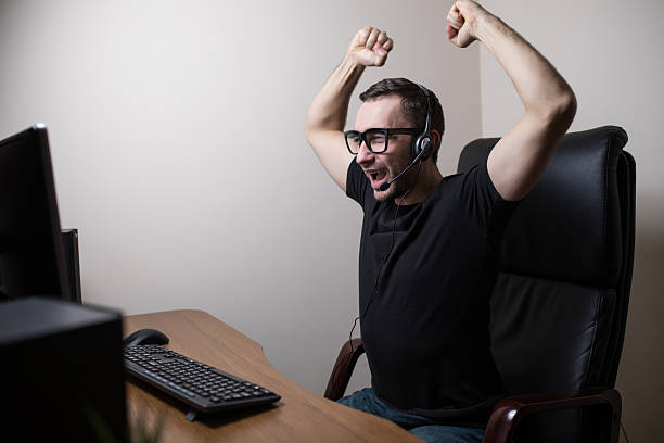 istock young man in eyeglasses with headset playing and winning computer 639612914