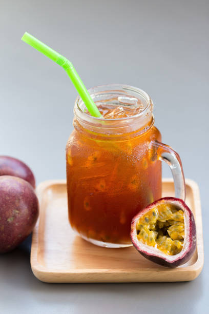 Fresh passion fruit juice with passion fruits on gray table.