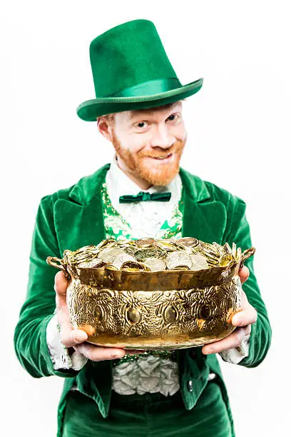 A stereotypical Irish character all ready for Saint Patricks day.  He smiles, holding a pot of gold.  Isolated studio shot on white background.