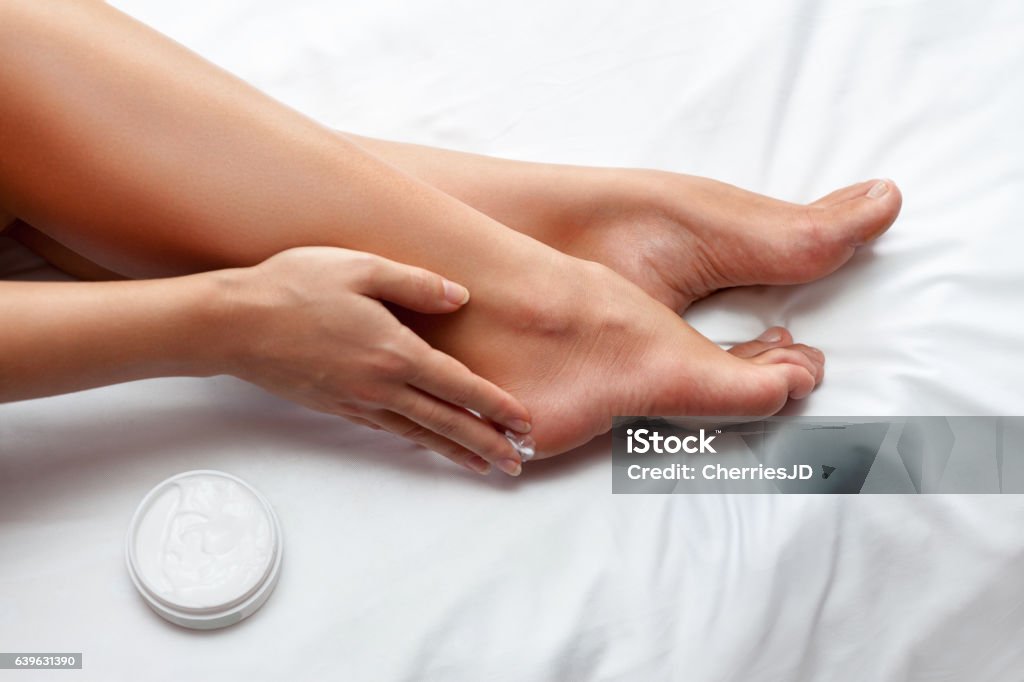 Skin care for feet Woman caring about her feet and putting hydrating cream on it Moisturizer Stock Photo