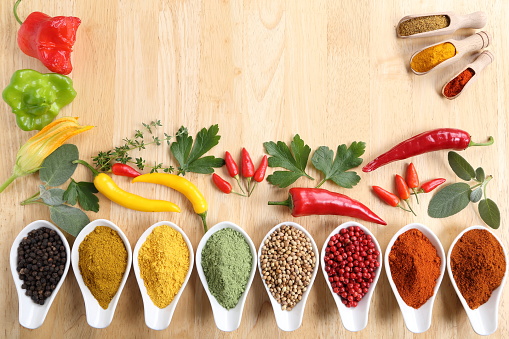 Aromatic and colorful spices in ceramic containers on a wooden background.