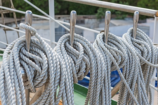 A blue nylon hawser rope, wrapped around a yellow steel cleat secures an industrial ship to  a mooring in the Cape Cod Canal