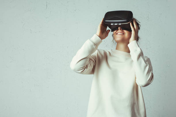 Handsome woman wearing virtual headset Handsome young woman wearing virtual headset. Smiling hipster using VR glasses. Blank sweater. White grunge wall with cracks background head mounted display stock pictures, royalty-free photos & images