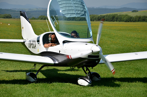 Ocova, Slovakia - August 2, 2014: Two men sit into ultralight propeller-driven airplane and get ready for taking off