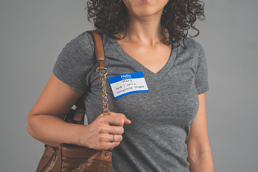 A single person in a studio wearing a nametag with a label about COMPULSIVE SHOPPING