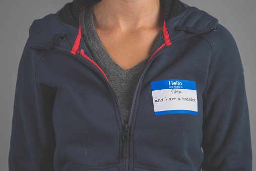A single person in a studio wearing a nametag with a label about HOARDING