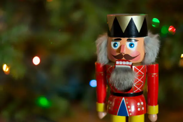 A classic nutcracker in front of a Christmas tree