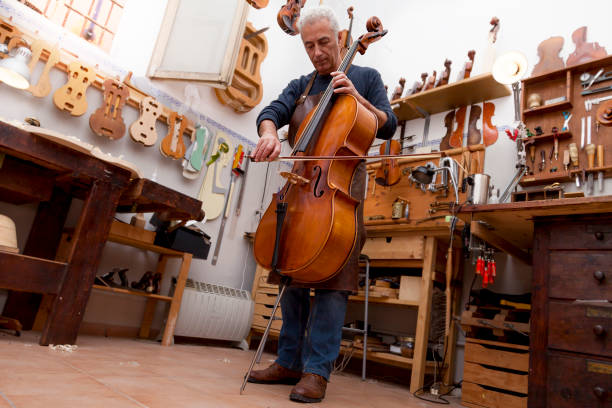 portrait of mature violin maker while testing the violins stock photo