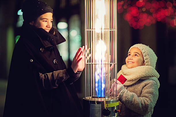 Girls are warming their hands on the gas heater Girls are warming their hands on the restaurant gas heater in the cold winter night young hot stock pictures, royalty-free photos & images