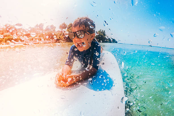 Cute, little surfer boy lying on the surfboard in the sea