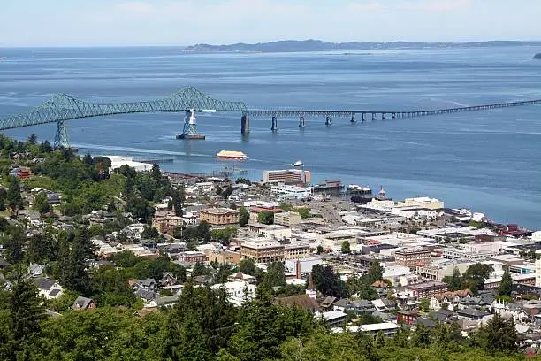 A high view of the port city of Astoria Oregon with its downtown buildings on the Columbia River with the Highway 101 bridge spanning the four mile mouth of the Columbia River. This is also the site of the movie called The Goonies.